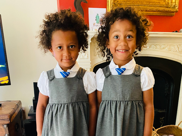 Two girls in grey school uniform smile at the camera