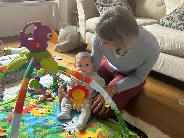 Gemma plays with a baby on a floor play mat