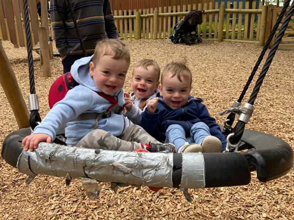 Triplets on a large swing at the park