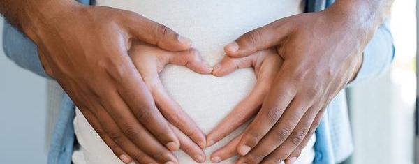 A pregnant women and her partner holds her bump