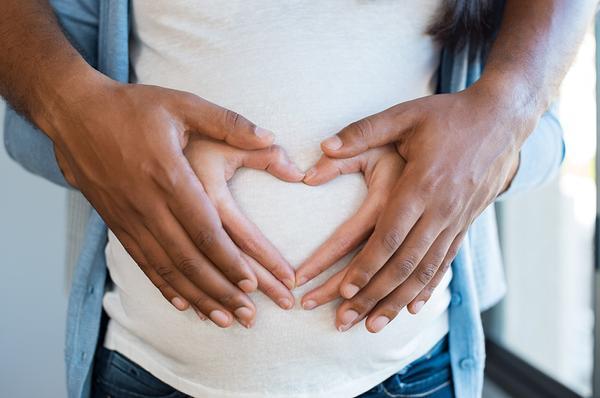 Pregnant woman holding her stomach with partner